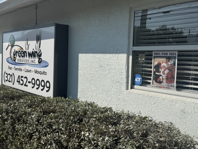 External shot of Green Wing Services sign and window with Toys for Tots poster on it